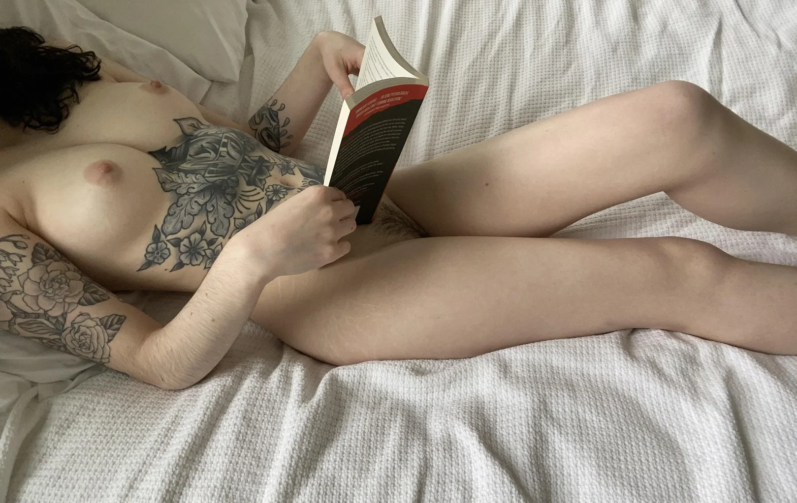dishonestpudding, 1girl, female only, breasts, nipples, pussy, areolae, female, medium hair, indoors, completely nude, medium breasts, bedroom, dark hair, naked, tattoos, nude, reddit, bed, legs, wavy hair, laying on bed, hairy, white woman, book