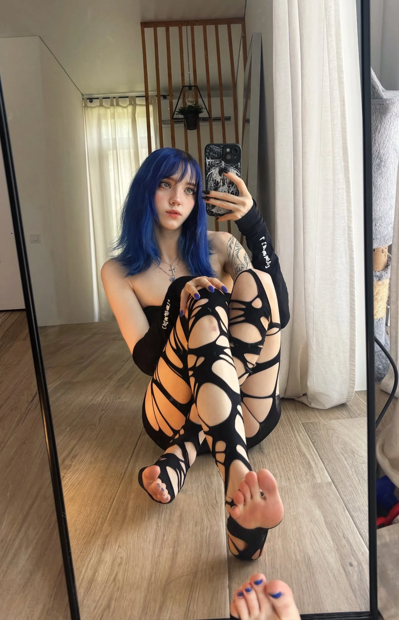 astasiangel, 1girl, female only, white female, caucasian female, light-skinned female, medium hair, front view, makeup, selfie, piercing, sitting, tattoos, fringe, bangs, dyed hair, feet, legwear, non-nude, nose piercing, black clothes, legs together, necklace, mirror selfie, on floor, blue eyes, black legwear, freckles, soles, blue hair, sitting on floor, bare shoulders, cross necklace, lip biting, black fingernails, torn, torn clothes, torn legwear, blue fingernails, blue toenails