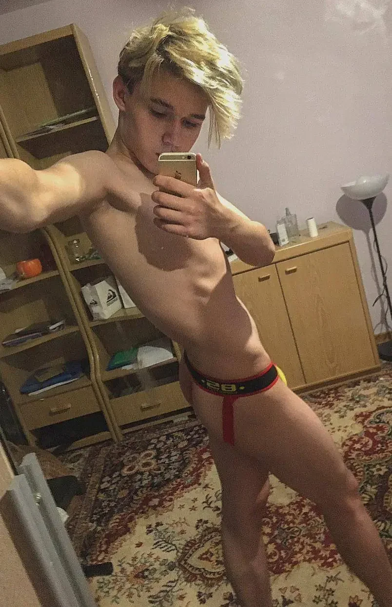 indoors, ass, standing, selfie, bedroom, solo, partially dressed, male, dyed hair, male only, 1boy, male focus, white male, mirror, short hair, underwear, phone, holding, holding phone, underwear only, male underwear, looking at phone, jockstrap